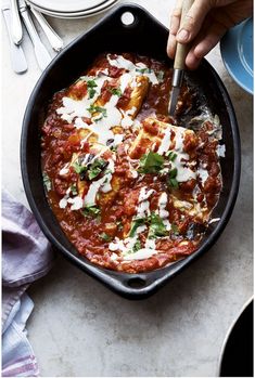 someone is cooking food in a skillet with sauce and parmesan cheese on top