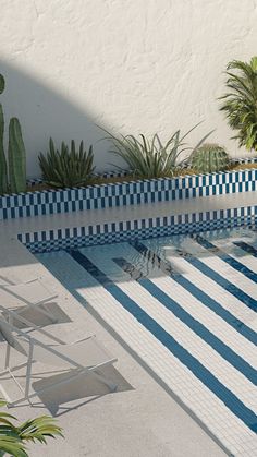 an empty swimming pool surrounded by plants and chairs