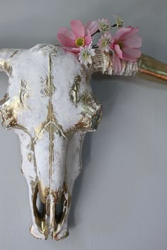 a cow skull with flowers on it's head hanging from a wall mounted hook