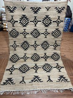 an old black and white rug with fringes on the floor in front of a wooden table