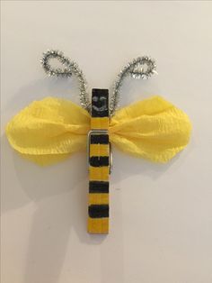 a yellow and black butterfly decoration hanging from a wall on a white surface with silver beads