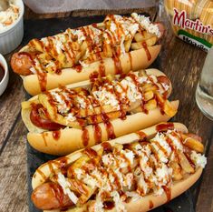 four hotdogs with toppings on them sitting on a table next to condiments