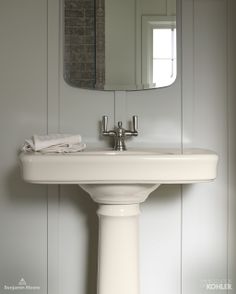 a white pedestal sink sitting under a bathroom mirror