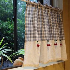 a kitchen window curtain with cherries hanging from it's valance in front of a potted plant