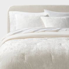 an unmade bed with white linens and pillows