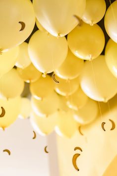 yellow balloons with smiley faces hanging from the ceiling and crescents attached to them, as if they were floating in the air