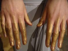 two hands with gold painted on them