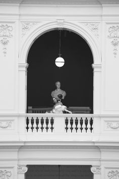 a black and white photo of a man sitting on a balcony