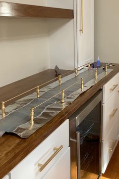 a kitchen with white cabinets and wooden counter tops that have been taped to the wall