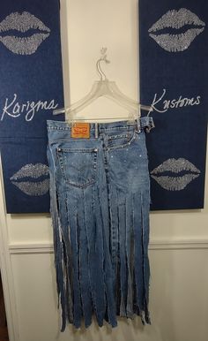 a pair of blue jeans hanging up against a wall with lipstick drawn on the side