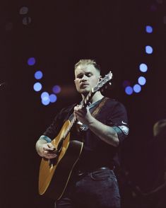 a man playing an acoustic guitar on stage