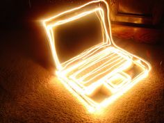 an open laptop computer sitting on top of a floor covered in bright neon lights,