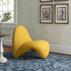 a yellow chair sitting on top of a blue rug in a living room next to a table