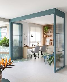 an office with glass walls and plants in the corner on either side of the room