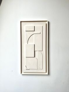 a white wall with a square shaped object on it's side and the letter f in the middle