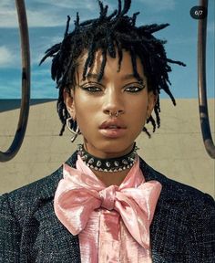 a woman with dreadlocks wearing a pink bow tie