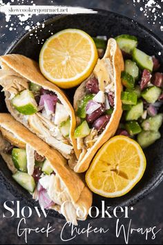 a bowl filled with chicken, cucumber and lemon slices on top of a table