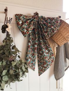 two pieces of cloth hanging on the wall next to some plants and wicker baskets