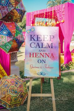 a sign that says keep calm and henna on with umbrellas in the background