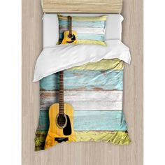 a bed with a guitar on it in front of a wooden wall and white sheets