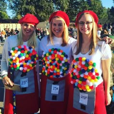 three women dressed in costumes made to look like they are holding up some candy balls