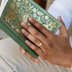 a person holding an open book in their left hand, with both hands on it