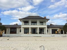 a large white house sitting on top of a sandy beach