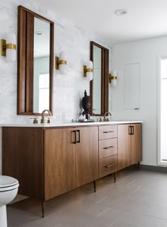 a bathroom with two sinks, mirrors and a toilet in the middle of the room