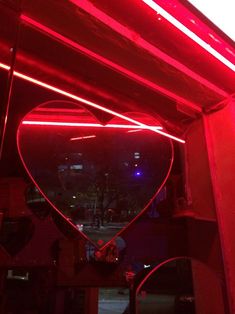 a heart shaped mirror hanging from the side of a building with red lights on it