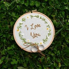 a cross stitch hoop with the words i love you on it sitting in some grass