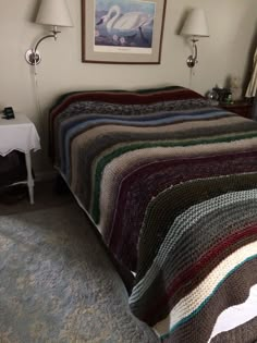 a bedroom with a bed covered in a multicolored blanket next to two lamps