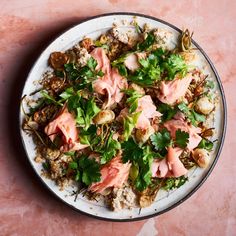 a white plate topped with meat and veggies on top of a pink table