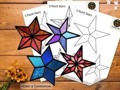 three different colored paper stars next to each other on a wooden surface with flowers in the background