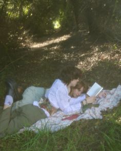 a woman laying on the ground reading a book