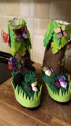 two shoes made out of paper sitting on top of a wooden table next to a stove