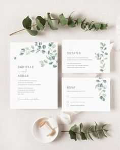 the wedding stationery is laid out with greenery