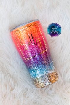 the tumbler is decorated with colorful glitters and has a monogrammed name on it