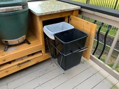 a trash can sitting on top of a wooden deck next to a grill and garbage can