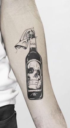 a man's arm with a bottle of wine and skull tattoo on the left forearm