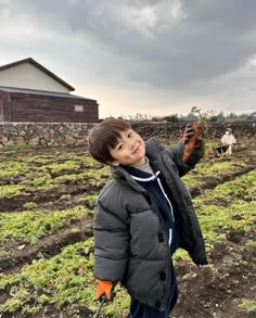 a young boy standing in the middle of a field