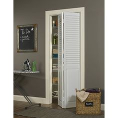 an open pantry door in a room with a chalkboard on the wall behind it