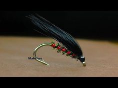 a black and red fly with green tips on it's tip, sitting on a brown surface