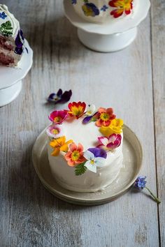 a white cake with flowers on it sitting on a plate next to another piece of cake