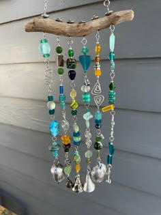 a wind chime hanging from a tree branch with beads and charms attached to it