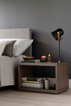 a bedroom with a bed, nightstand and lamp on the side table next to it