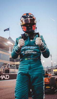 a man standing in front of a race car with his hands on his hips and wearing a helmet