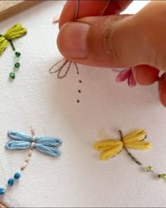 someone is stitching dragonflies on a white cloth