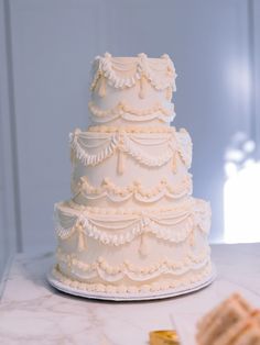 a three tiered white cake sitting on top of a table next to crackers