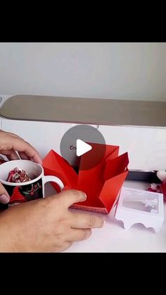 two hands are holding cups and making origami flowers out of coffee mugs