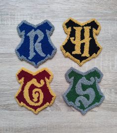 four harry potter inspired patches sitting on top of a wooden table